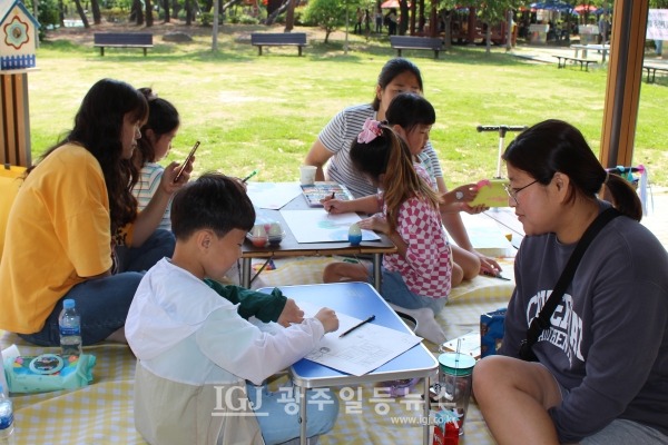 「제18회 운남동 목련마을 사생대회」가 한창인 운남근린공원에서 그림 그리기에 열중인 어린이와 이를 지켜보는 엄마들 모습.