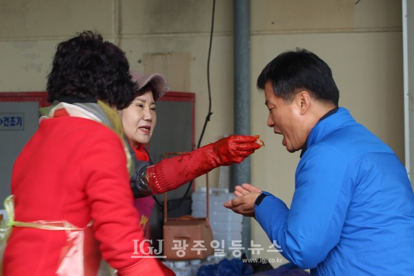 송정농협 농가주부모임 회원이 박균택 변호사에게 갓 담은 김장 김치로 수육을 싸서 입에 넣어 주고 있다.